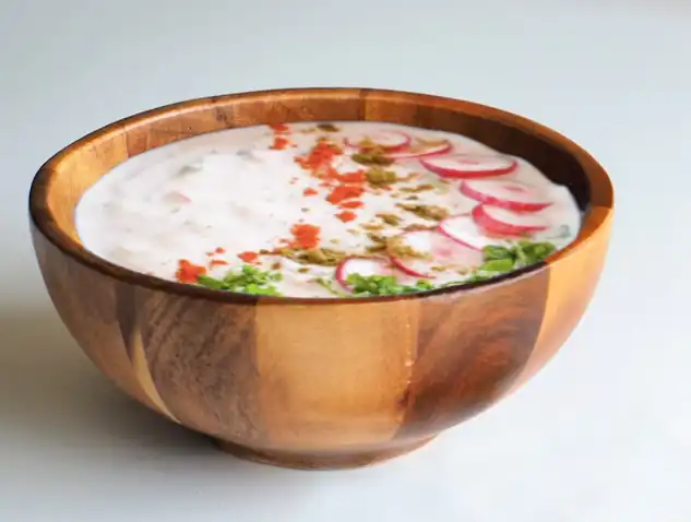 Raita rinfrescante con coriandolo e ravanello, piatto di yogurt fresco con un morso croccante, perfetto come contorno ayurvedico nutriente.